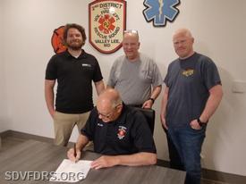 SDVFD&RS President Blair Swann signs the solar energy contract as (from left to right) Gregg Havens of Energy Select, Jay Rodgers Solar Committee Chairman, and 2nd DVFD&RS Treasurer Mike Scrivener look on.